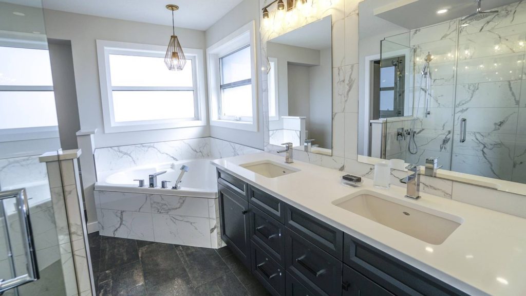 Salle de bain avec baignoire d'angle, double vasque et douche à l'italienne, faïence effet marbre