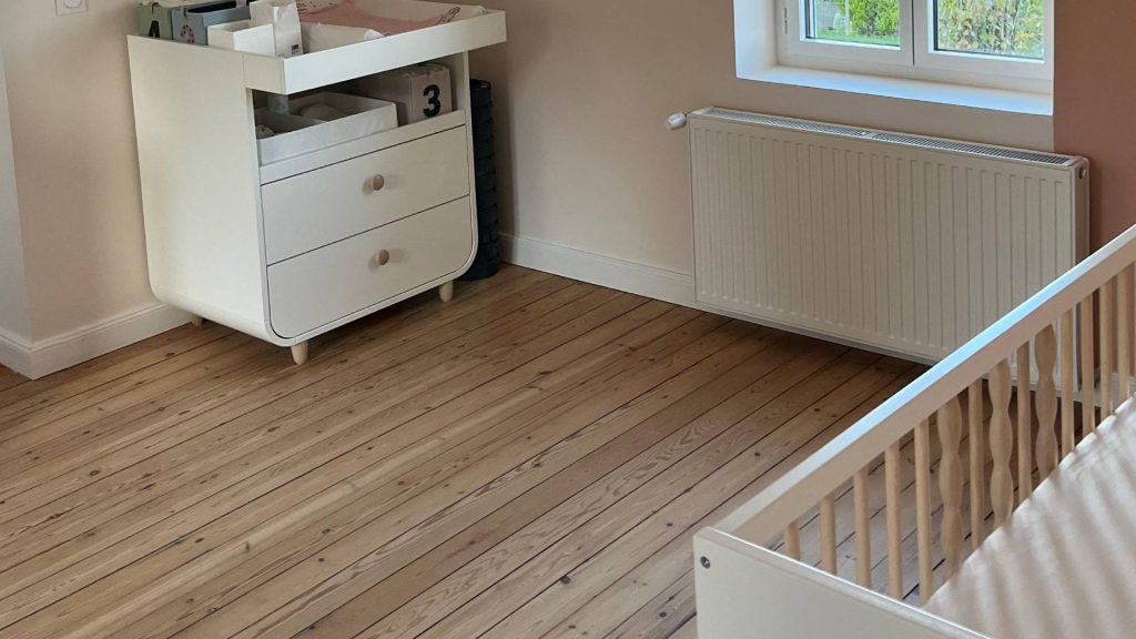 Parquet en lames de pin poncé dans une chambre d'enfant, sous une fenêtre